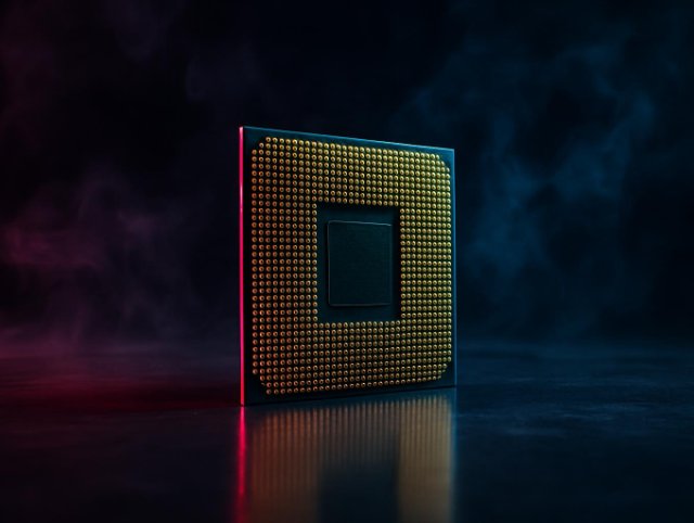 Processor chip standing on edge showing its gold contact grid under warm light